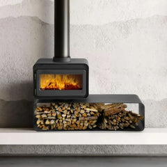 Modern wood stove with fire burning inside and a metal log holder on a light gray background